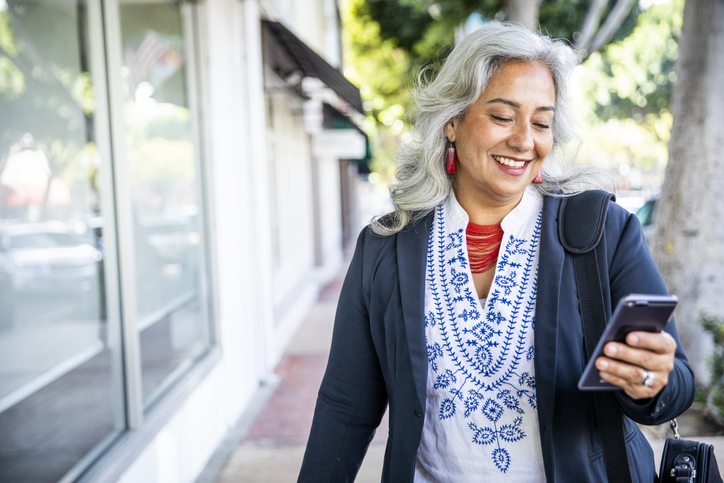 fashionable older woman using a smartphone while out and about.