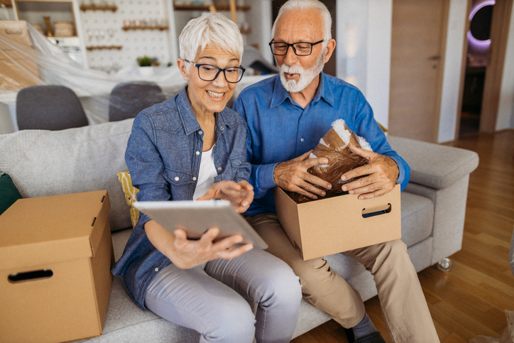 Senior couple packing items and looking at iPad.