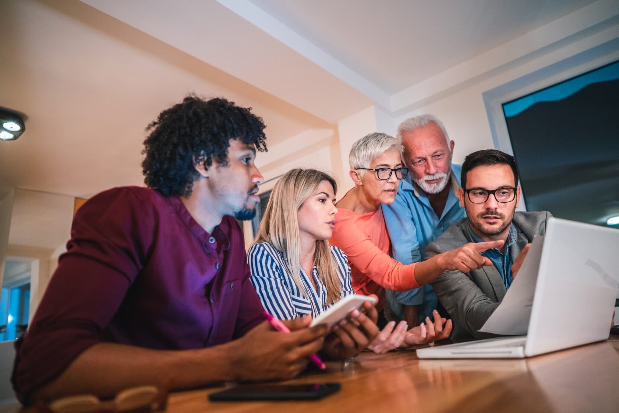 Family consults computer together at dining room table.