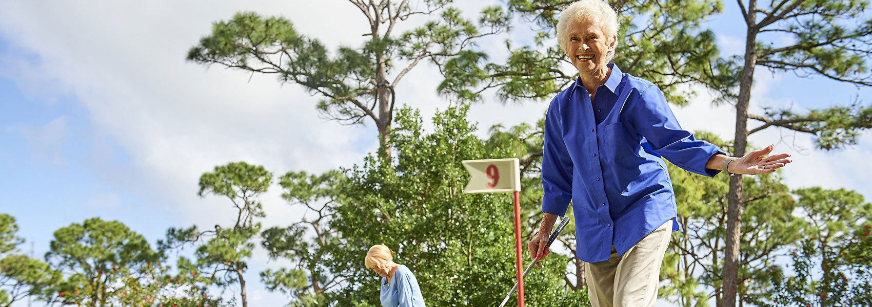 A senior woman celebrating her golf shot while playing on the golf course at her Delray Beach retirement community