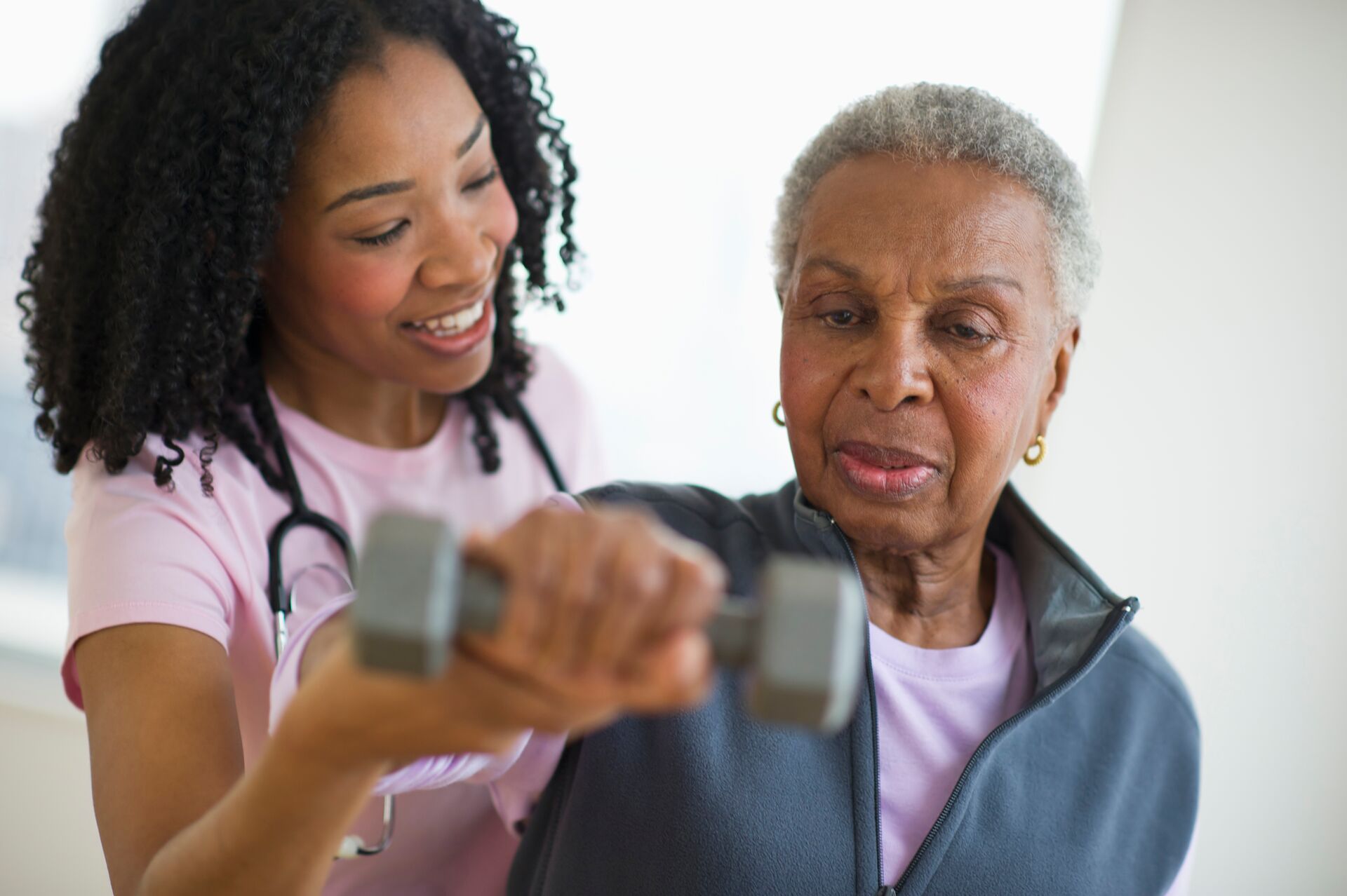 Nurse helping senior woman do physical therapy exercises